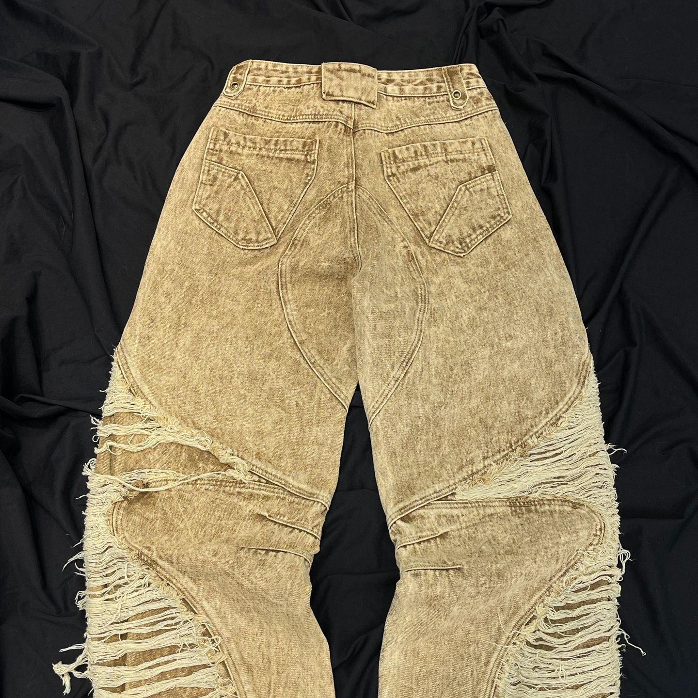 BladeWasteland distressed streetwear pants back view showing heavy ripped panels and faded desert yellow wash