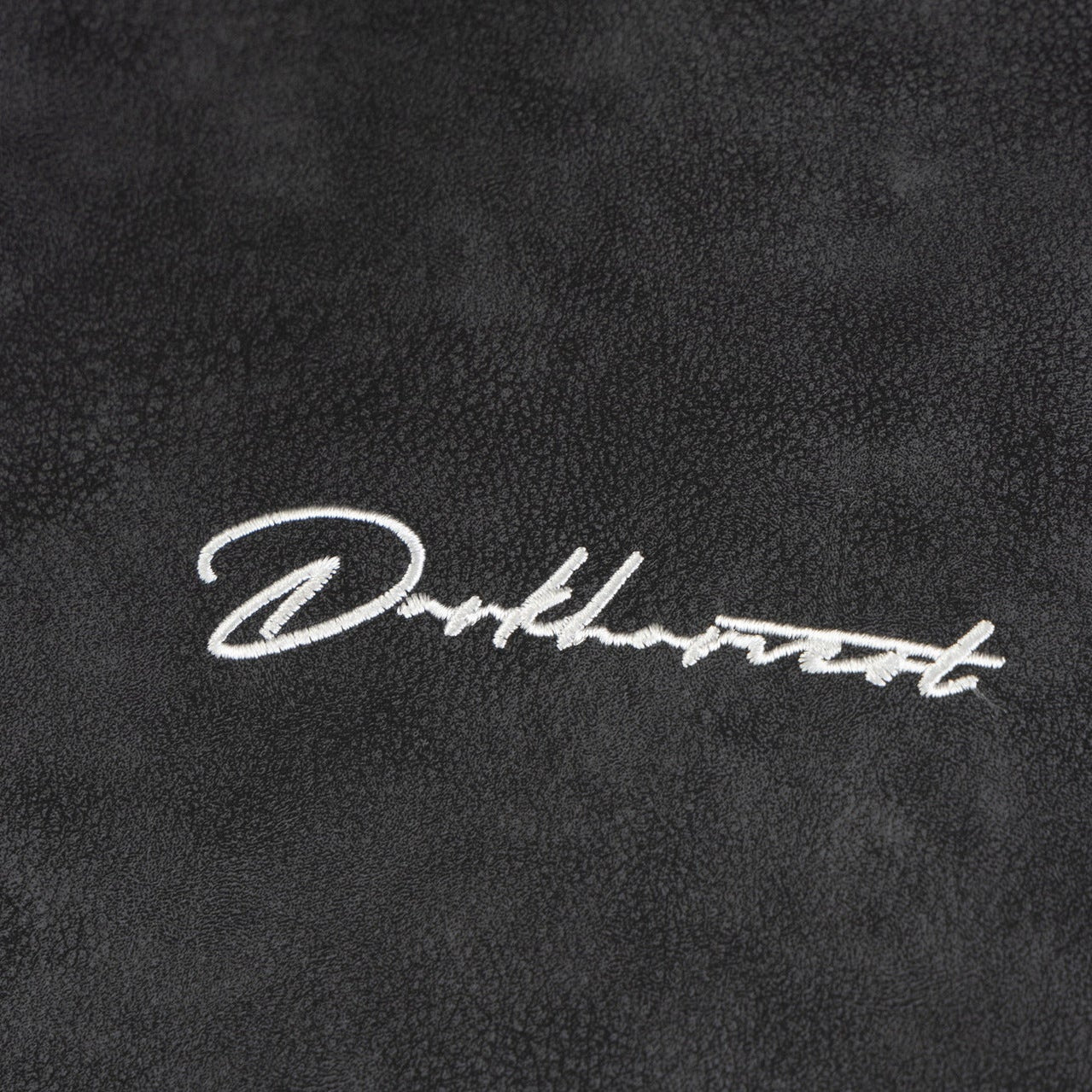 Close up embroidery detail of Darkharvest logo on ARC NightDye black vintage streetwear jacket