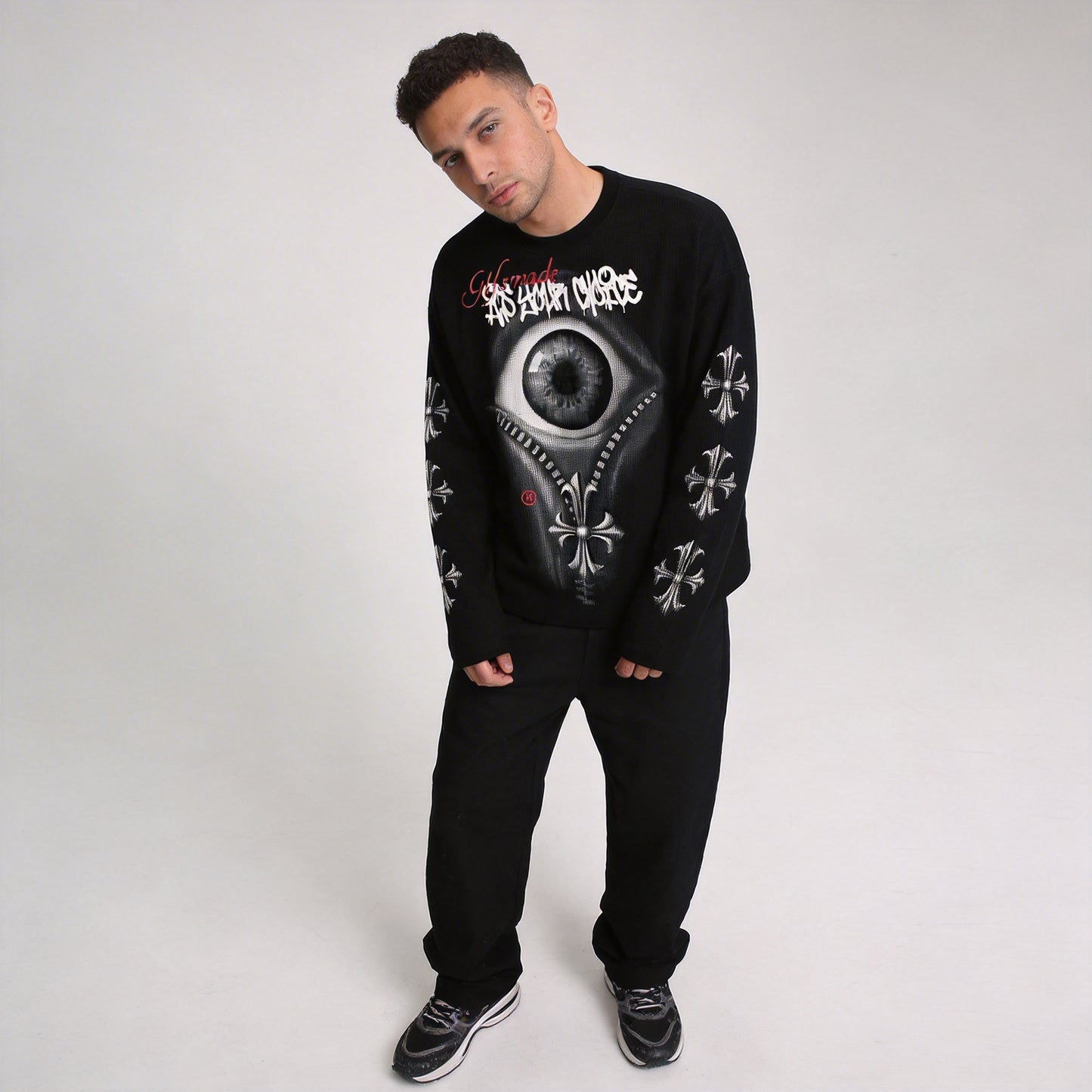 Male model posing in black VoidVision eye graphic long sleeve streetwear shirt with gothic cross sleeve prints